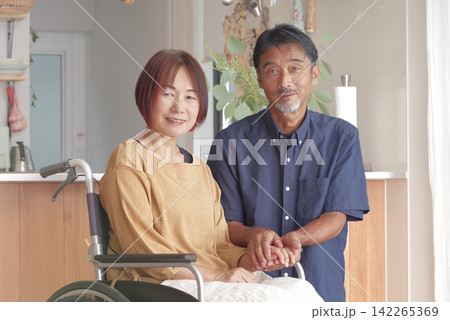 車椅子にすわる妻と寄り添う夫 車椅子にすわる妻と寄り添う夫 142265369
