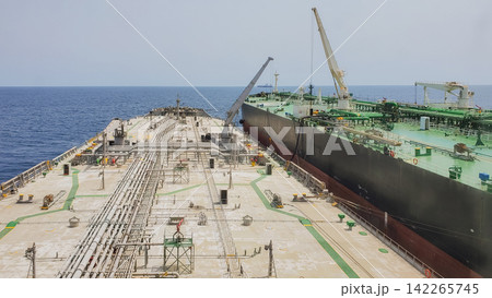 Ship to ship STS oil transfer operation between two large crude tankers alongside each other in calm open sea water stock photo Ship to ship STS oil transfer operation between two large crude tankers alongside each other in calm open sea water stock photo 142265745