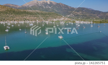 Aerial drone view of calm Nidri bay full of white anchored sailing boats against majestic mountains on sunny day in Lefkada Greece stock photo Aerial drone view of calm Nidri bay full of white anchored sailing boats against majestic mountains on sunny day in Lefkada Greece stock photo 142265751