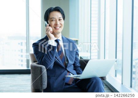 椅子に座って、スマホで会話する日本人男性 142266250