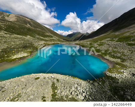 Bright turquoise mountain lake in valley under cloudy sky Bright turquoise mountain lake in valley under cloudy sky 142266449