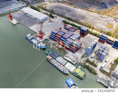 Aerial view of barges loading cargo and a container yard at a riverside terminal in Ho Chi Minh City, Vietnam Aerial view of barges loading cargo and a container yard at a riverside terminal in Ho Chi Minh City, Vietnam 142268050