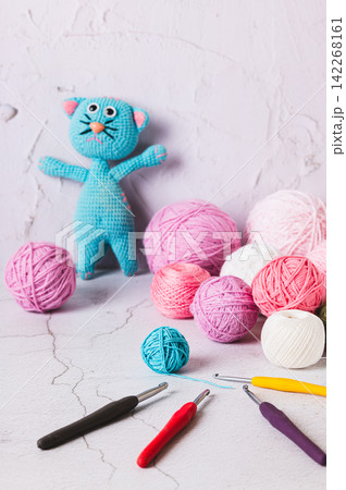 Balls of yarn and crochet hooks, a knitted toy on the table vertical view 142268161