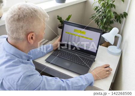 Senior Professional Taking Notes While Analyzing Mortgage Amortization Table on Laptop Screen Senior Professional Taking Notes While Analyzing Mortgage Amortization Table on Laptop Screen 142268500