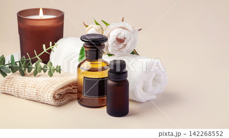 Spa and wellness composition with essential oil, aroma burning candles, and towels on beige background Spa and wellness composition with essential oil, aroma burning candles, and towels on beige background 142268552