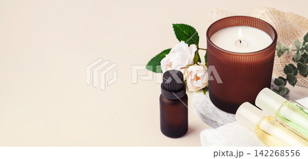 Spa and wellness background with burning aromatherapy candle, essential oil bottles and flower 142268556