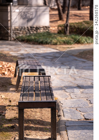 Close up of wooden bench, with stone pathway on the background in public park 142268578