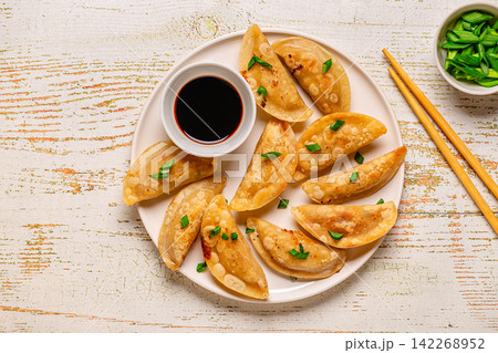 Dumplings served on a plate with soy sauce 142268952