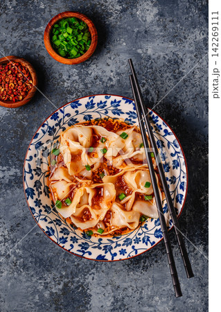 Wontons are placed in a bowl with spicy sauce. Wontons are placed in a bowl with spicy sauce. 142269111
