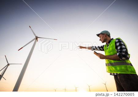 Wind Energy Worker Pointing Toward Turbines at Sunset Wind Energy Worker Pointing Toward Turbines at Sunset 142270005