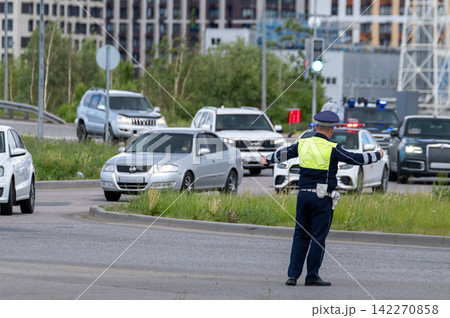Traffic police officer directing cars at busy urban intersection during daytime traffic control operation Traffic police officer directing cars at busy urban intersection during daytime traffic control operation 142270858