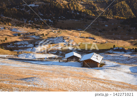 Traditional mountain huts on snow-covered alpine meadows 142271021