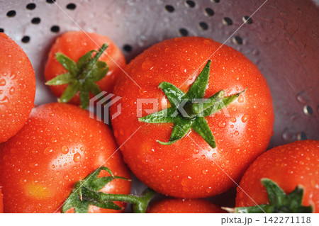 Ripe tomatoes in colander with visible green stems Ripe tomatoes in colander with visible green stems 142271118