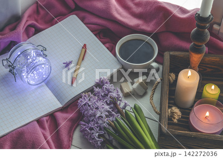 Early spring still life scene. Cup of coffee and marshmallow, opened notebook, pink plaid and candles on windowsill. Cozy Easter, vintage feminine styled photo Early spring still life scene. Cup of coffee and marshmallow, opened notebook, pink plaid and candles on windowsill. Cozy Easter, vintage feminine styled photo 142272036