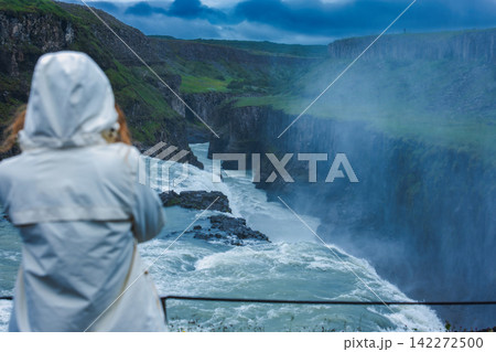 Traveler Overlooking Powerful Waterfall Canyon in Iceland 142272500