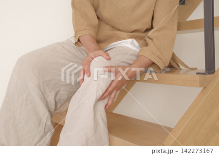 階段の上り下りで膝に痛みを感じる女性 142273167