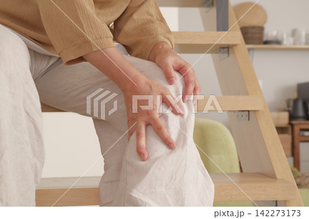 階段の上り下りで膝に痛みを感じる女性 142273173