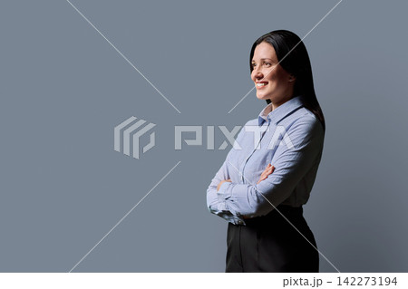 Confident businesswoman standing with arms crossed on gray studio background Confident businesswoman standing with arms crossed on gray studio background 142273194