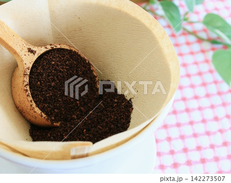 ペーパーフィルターに入れた挽いたコーヒーと木製スプーン ペーパーフィルターに入れた挽いたコーヒーと木製スプーン 142273507
