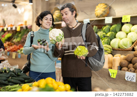Couple man and woman choosing cauliflower and cucumbers Couple man and woman choosing cauliflower and cucumbers 142273882