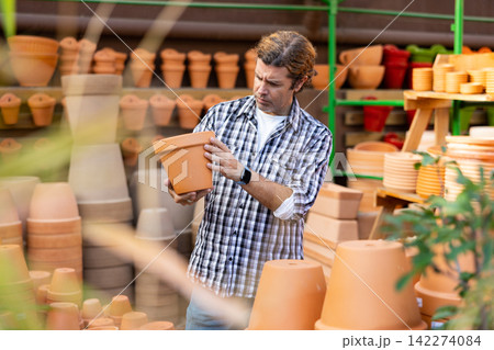 Focused man choosing pots for growing houseplants in gardening store Focused man choosing pots for growing houseplants in gardening store 142274084