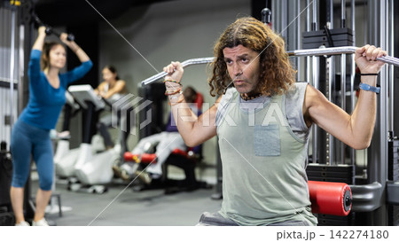 Caucasian sportsman doing reps on lat pull down machine in gym Caucasian sportsman doing reps on lat pull down machine in gym 142274180
