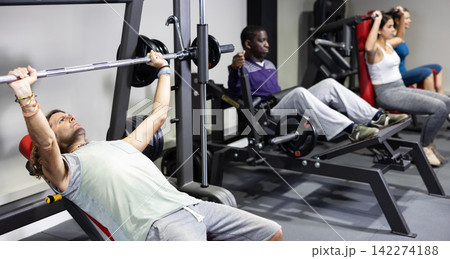 Muscular man doing barbell exercises in gym Muscular man doing barbell exercises in gym 142274188