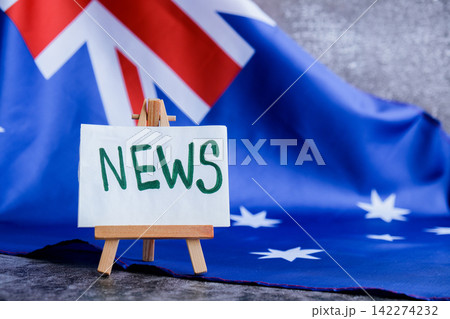 Flag-themed board with NEWS text for media headlines. Patriotic mockup with text NEWS Vibrant Australian flag background trending for current affairs content. Concept of national reporting Flag-themed board with NEWS text for media headlines. Patriotic mockup with text NEWS Vibrant Australian flag background trending for current affairs content. Concept of national reporting 142274232