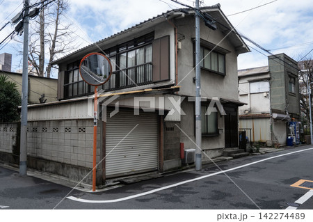 下町の路地裏に建つ古い二階建ての民家、トタン屋根の車庫とブロック塀のノスタルジックな外観 下町の路地裏に建つ古い二階建ての民家、トタン屋根の車庫とブロック塀のノスタルジックな外観 142274489