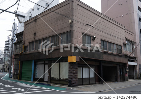 角地に建つ昭和レトロな看板建築、シャッターが閉ざされた古い店舗兼住宅の外観 角地に建つ昭和レトロな看板建築、シャッターが閉ざされた古い店舗兼住宅の外観 142274490