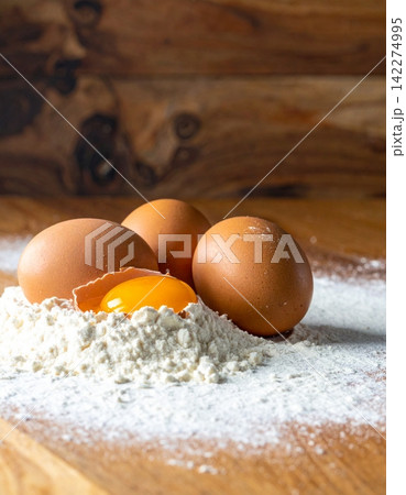 white flour on a wooden surface with fresh brown eggs 142274995