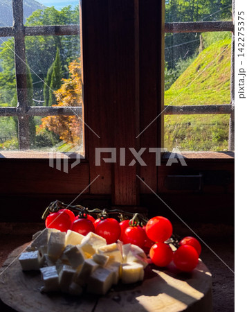 Rustic window view with tomatoes and cheese snack 142275375