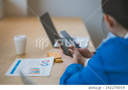 ワイヤレス通信をしようとスマホ同士を近づけるオフィスで働く若い男女 ワイヤレス通信をしようとスマホ同士を近づけるオフィスで働く若い男女 142276059