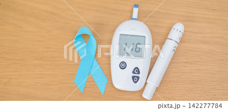 digital blood glucose meter with lancet pen and Blue Ribbon on table. high blood sugar level, November World Diabetes Day, Awareness month, Glycemia,, Hyperglycemia and insulin testing and checking digital blood glucose meter with lancet pen and Blue Ribbon on table. high blood sugar level, November World Diabetes Day, Awareness month, Glycemia,, Hyperglycemia and insulin testing and checking 142277784