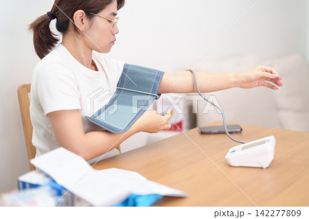 woman checking Blood pressure by Blood pressure monitor with Cuff. Systolic, SYS, Diastolic, DIA, Pulse, Hypertension, Hypotension, Heart rate, Cardiovascular Disease and May World hypertension day 142277809
