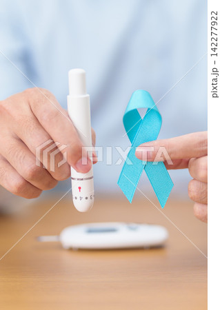 Hand show Blue Ribbon and digital blood glucose meter with lancet pen. high blood sugar level, November World Diabetes Day, Awareness month, Glycemia,, Hyperglycemia and insulin testing and checking Hand show Blue Ribbon and digital blood glucose meter with lancet pen. high blood sugar level, November World Diabetes Day, Awareness month, Glycemia,, Hyperglycemia and insulin testing and checking 142277922