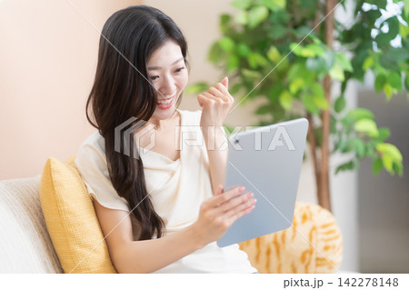 タブレットを見て喜ぶ若い女性(ガッツポーズ) タブレットを見て喜ぶ若い女性(ガッツポーズ) 142278148