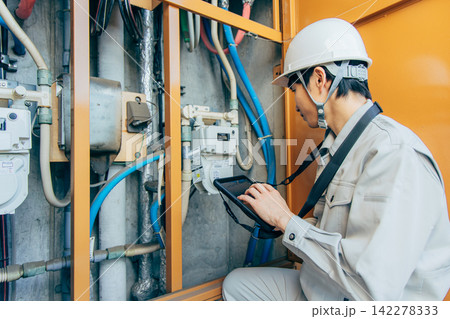 マンションの廊下で点検作業をする若い男性 マンションの廊下で点検作業をする若い男性 142278333