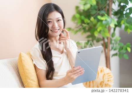 タブレットを持って微笑む若い女性 タブレットを持って微笑む若い女性 142278341