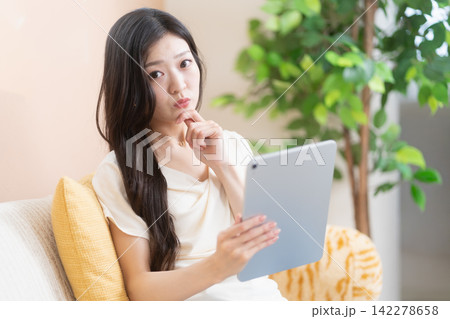 タブレット端末を持って考えこむ若い女性 タブレット端末を持って考えこむ若い女性 142278658