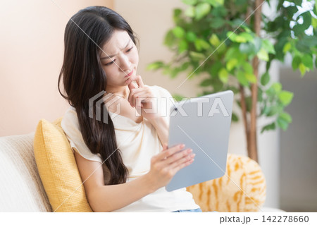 タブレット端末を持って考えこむ若い女性 タブレット端末を持って考えこむ若い女性 142278660