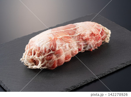 黒のスレートプレートに置かれたネット入り生の豚肉ブロック チャーシュー用たこ糸ネット付き 黒背景 142278926