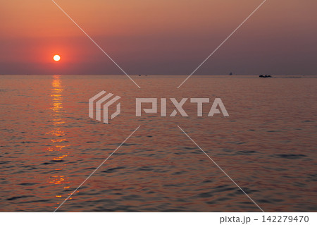 Sunset over a calm sea casts a golden reflection across rippling water Sunset over a calm sea casts a golden reflection across rippling water 142279470