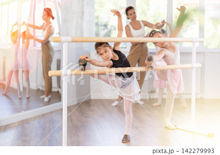 Little ballerinas together with choreography teacher in grand batman pose learn to dance ballet Little ballerinas together with choreography teacher in grand batman pose learn to dance ballet 142279993