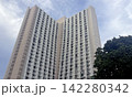 Towering residential building with many windows against a cloudy sky Towering residential building with many windows against a cloudy sky 142280342