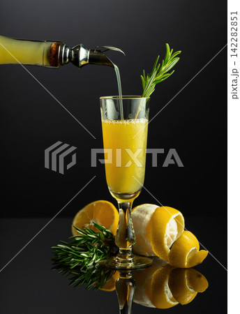 Traditional Italian liqueur Limoncello with rosemary twig on a black reflective background. Traditional Italian liqueur Limoncello with rosemary twig on a black reflective background. 142282851