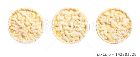 Puffed corn cakes, side by side, isolated, from above. Round, flat hard discs, with a textured, bumpy surface and light golden-yellow color, eaten as a snack or used as a base for ingredients. Photo Puffed corn cakes, side by side, isolated, from above. Round, flat hard discs, with a textured, bumpy surface and light golden-yellow color, eaten as a snack or used as a base for ingredients. Photo 142283329