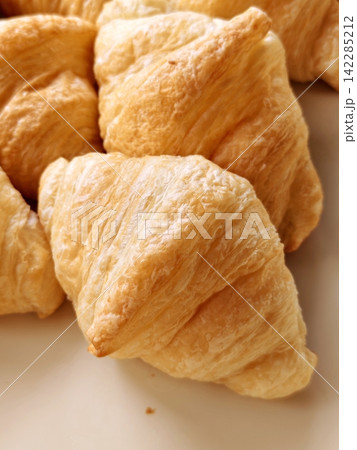 Macro shot of crispy golden butter croissants stacked on a plate. 142285212