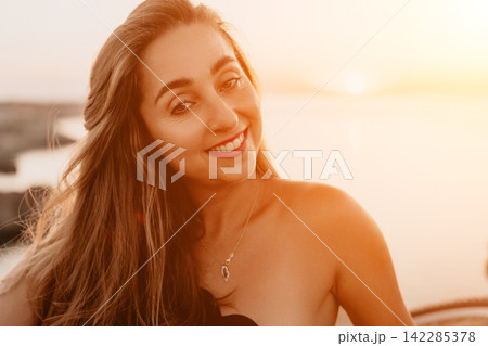Woman sunset smile portrait of a beautiful happy female enjoying the golden hour light by the coast during vacation Woman sunset smile portrait of a beautiful happy female enjoying the golden hour light by the coast during vacation 142285378