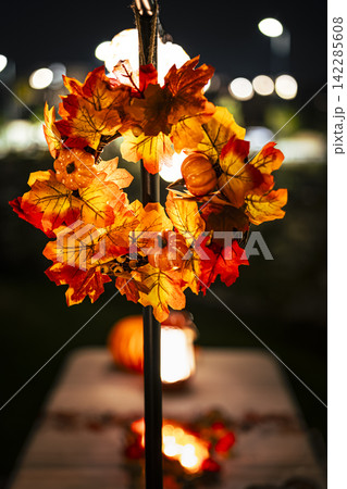 Vibrant autumn wreath on a pole in an outdoor night setting illustrates a warm seasonal centerpiece for festive evenings. Vibrant autumn wreath on a pole in an outdoor night setting illustrates a warm seasonal centerpiece for festive evenings. 142285608